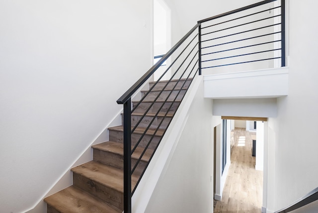 stairway with hardwood / wood-style floors and a towering ceiling