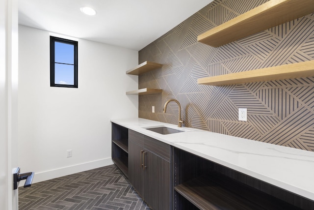 kitchen featuring dark brown cabinets, light stone counters, and sink