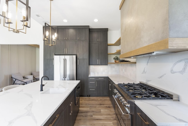 kitchen featuring light stone countertops, wall chimney range hood, sink, wood-type flooring, and high quality appliances