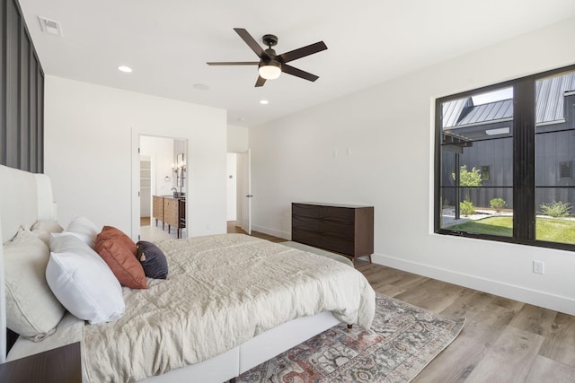 bedroom with connected bathroom, light hardwood / wood-style floors, and ceiling fan