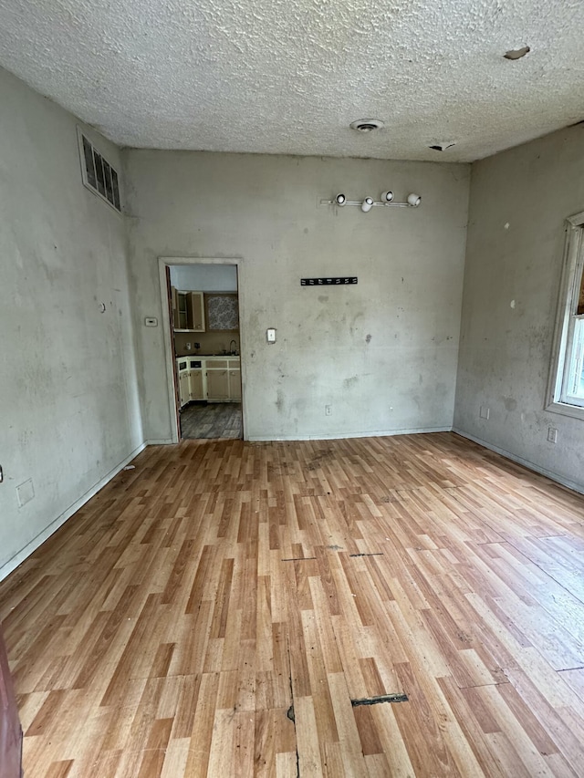 spare room with a textured ceiling and light wood-type flooring