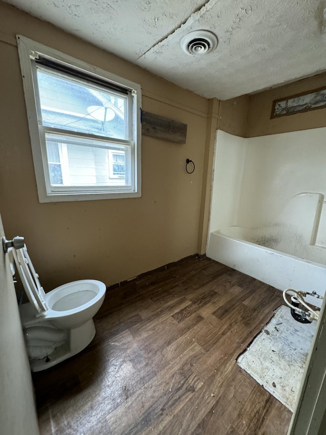 bathroom with hardwood / wood-style floors, a textured ceiling, and toilet