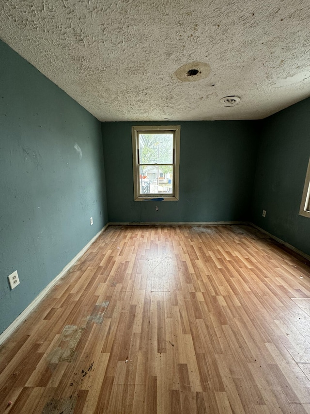 spare room with a textured ceiling and light hardwood / wood-style flooring