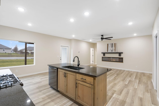 kitchen featuring dark stone countertops, dishwasher, sink, and light hardwood / wood-style floors