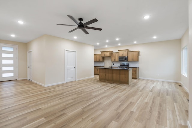 kitchen featuring ceiling fan, sink, a kitchen island with sink, appliances with stainless steel finishes, and light wood-type flooring