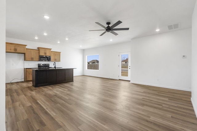 kitchen featuring sink, a center island with sink, appliances with stainless steel finishes, dark hardwood / wood-style flooring, and ceiling fan