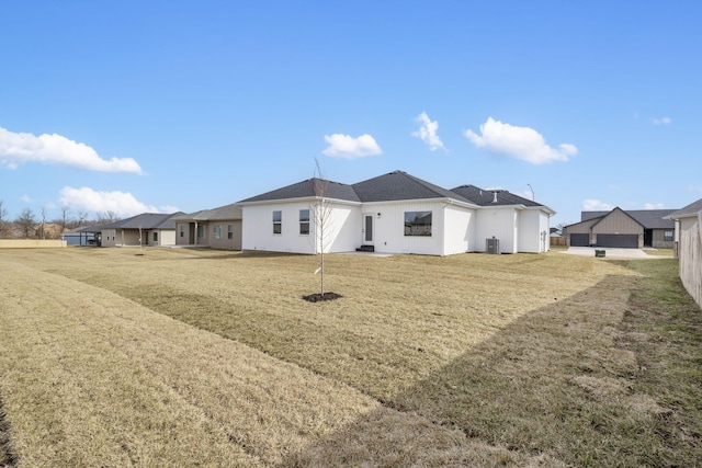 rear view of house with cooling unit and a lawn