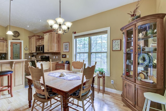 dining area with light wood-type flooring and an inviting chandelier