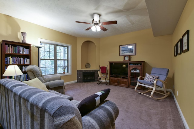 carpeted living room with ceiling fan, a fireplace, and a textured ceiling