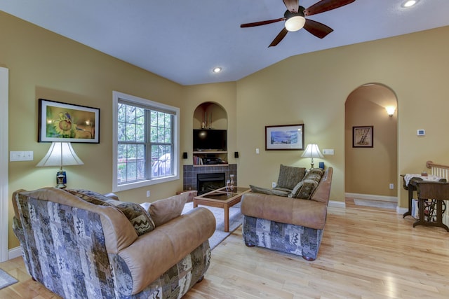 living room featuring ceiling fan, a fireplace, lofted ceiling, and light hardwood / wood-style flooring