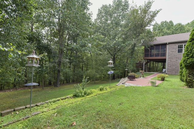 view of yard featuring a patio, an outdoor fire pit, and a sunroom