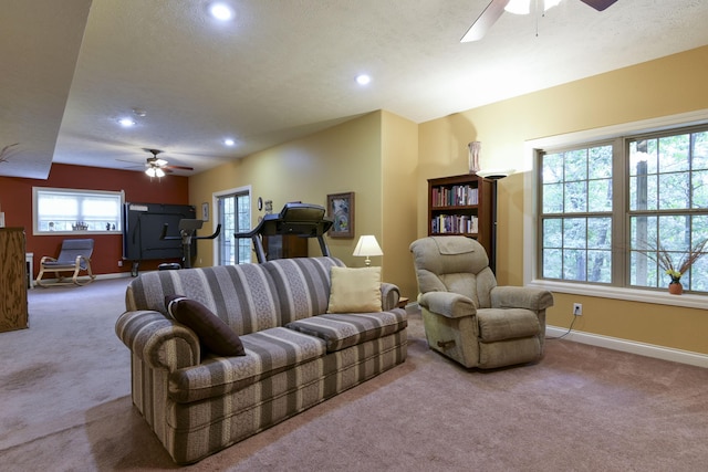 living room with ceiling fan, carpet floors, and a textured ceiling