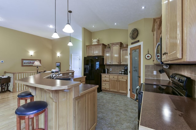 kitchen featuring a kitchen island with sink, black appliances, hanging light fixtures, decorative backsplash, and light brown cabinetry