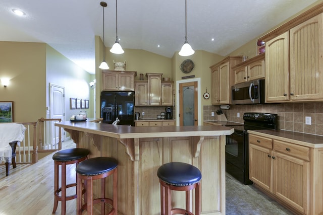 kitchen featuring hanging light fixtures, a kitchen island with sink, and black appliances