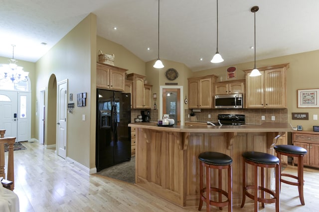 kitchen featuring black appliances, decorative light fixtures, vaulted ceiling, and tasteful backsplash