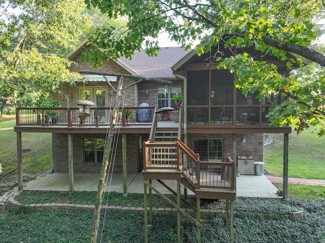 rear view of property featuring a sunroom, a yard, a patio, and a deck