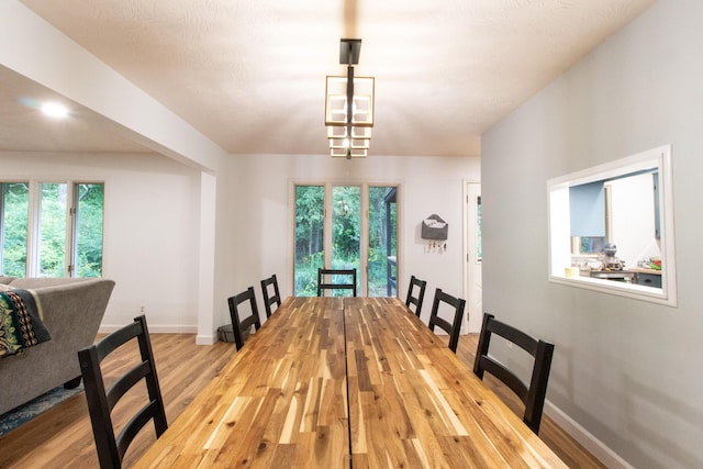 dining area with light hardwood / wood-style flooring and an inviting chandelier