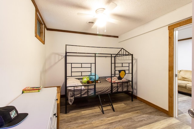 bedroom with ceiling fan, light wood-type flooring, and a textured ceiling