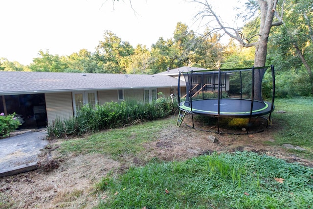 view of yard with a trampoline and french doors