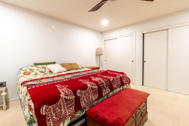 carpeted bedroom featuring ceiling fan and two closets