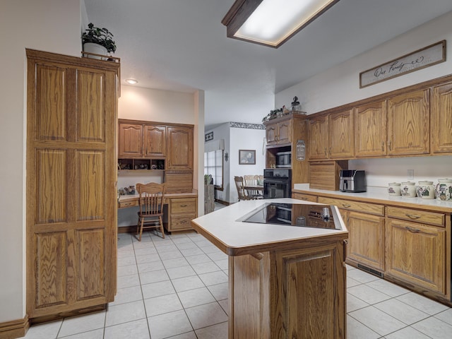 kitchen featuring light tile patterned floors, built in desk, a center island with sink, and black appliances