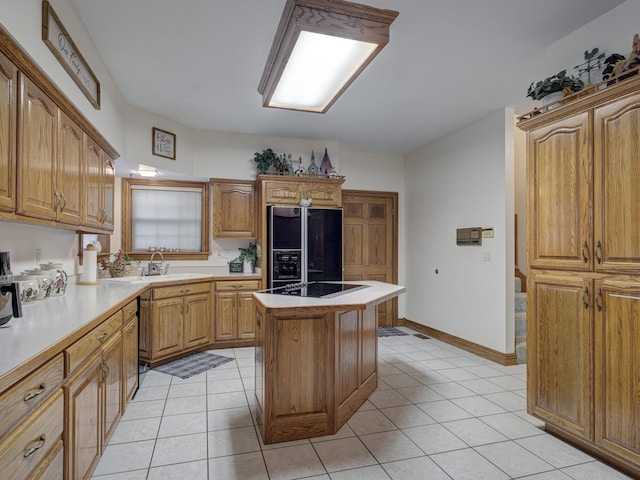 kitchen with a center island, light tile patterned floors, black appliances, and sink