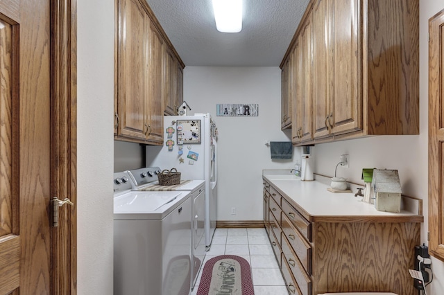 washroom with washing machine and dryer, light tile patterned floors, cabinets, and a textured ceiling