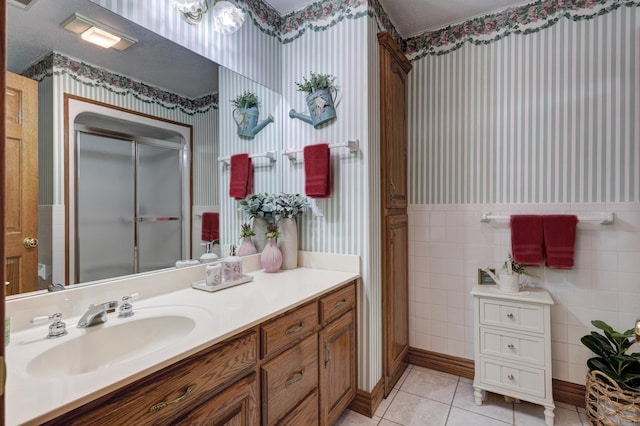 bathroom with tile patterned flooring, vanity, an enclosed shower, and tile walls