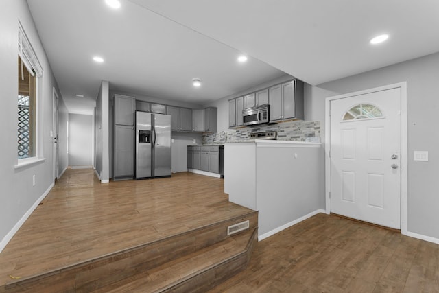 kitchen with gray cabinetry, decorative backsplash, stainless steel appliances, and dark wood-type flooring