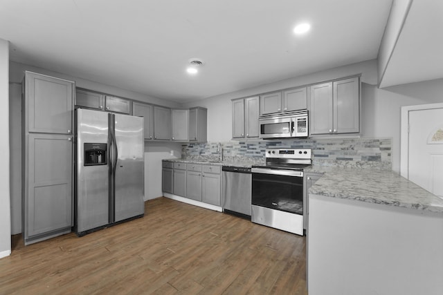 kitchen with sink, dark hardwood / wood-style floors, backsplash, gray cabinets, and appliances with stainless steel finishes