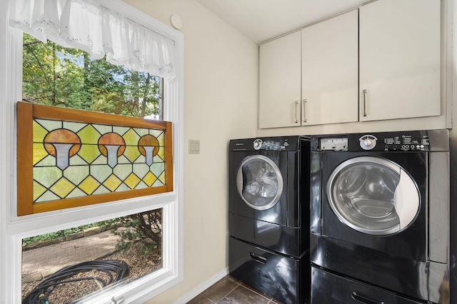 washroom with cabinets, washer and dryer, and dark tile patterned flooring