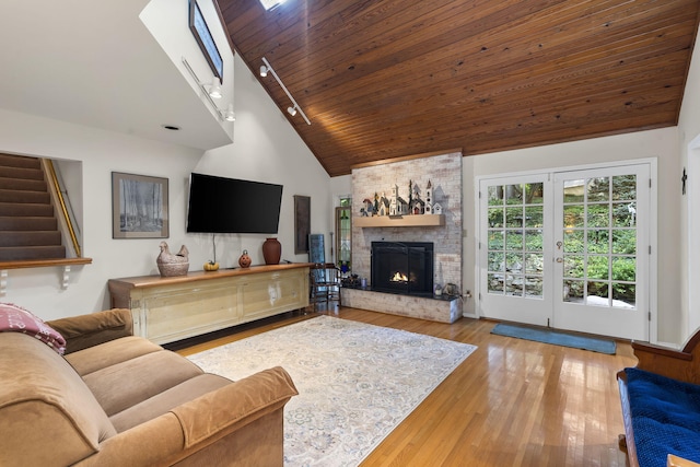 living room featuring a brick fireplace, light wood-type flooring, high vaulted ceiling, and wooden ceiling