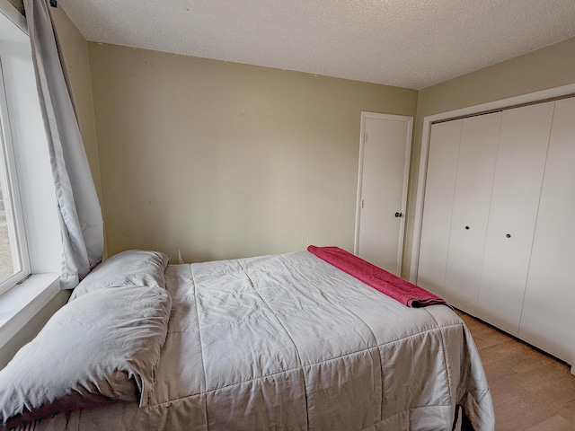 bedroom with light hardwood / wood-style flooring, a textured ceiling, and a closet
