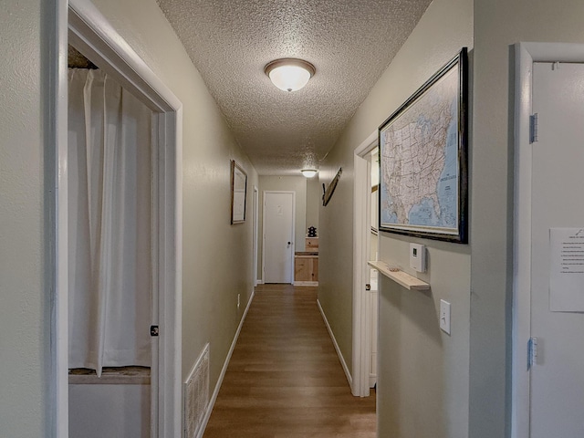 hall featuring wood-type flooring and a textured ceiling