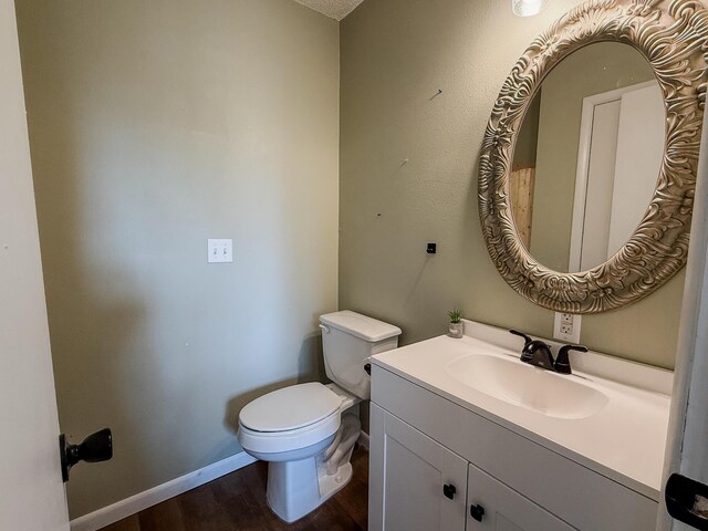 bathroom with toilet, vanity, and hardwood / wood-style flooring