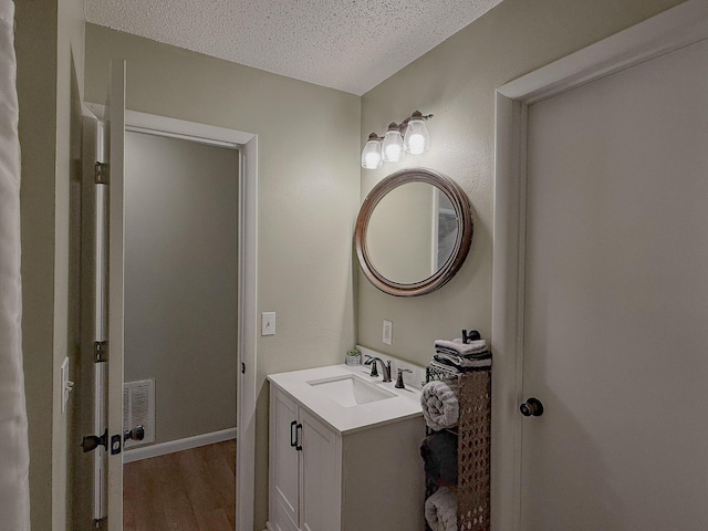 bathroom with hardwood / wood-style floors, vanity, and a textured ceiling