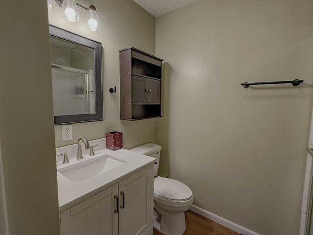 bathroom with hardwood / wood-style floors, vanity, toilet, a textured ceiling, and an enclosed shower