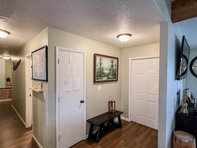 corridor with a textured ceiling and dark hardwood / wood-style floors