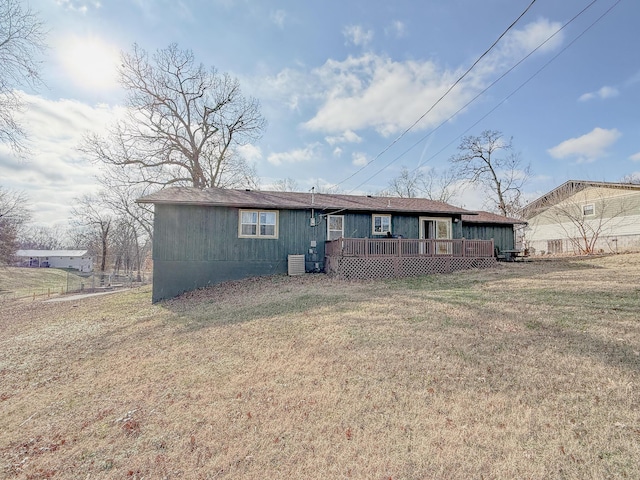 rear view of house featuring central air condition unit and a lawn