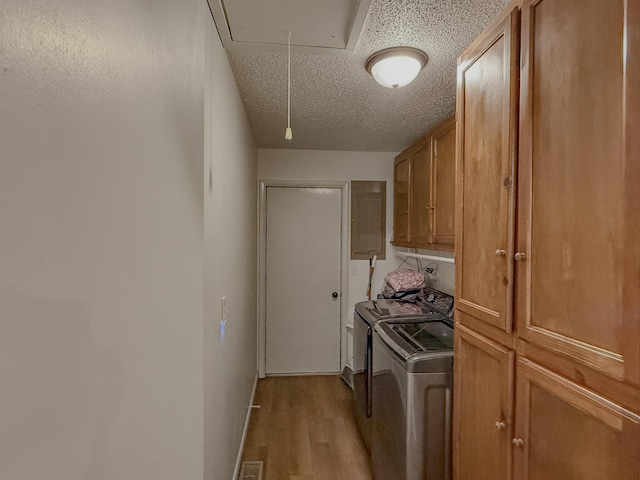 laundry area featuring washing machine and dryer, cabinets, a textured ceiling, and light wood-type flooring