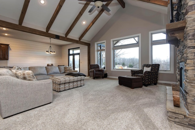 carpeted living room with beam ceiling, ceiling fan with notable chandelier, high vaulted ceiling, and wood walls