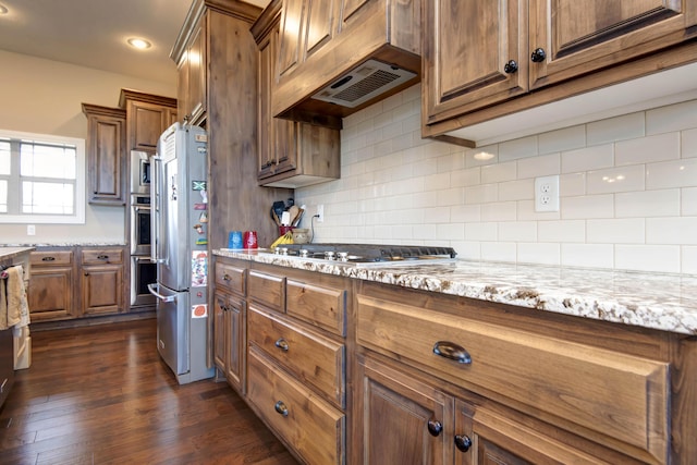 kitchen featuring custom exhaust hood, dark hardwood / wood-style floors, decorative backsplash, light stone countertops, and appliances with stainless steel finishes