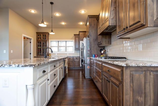 kitchen with stainless steel appliances, sink, a center island with sink, white cabinets, and hanging light fixtures