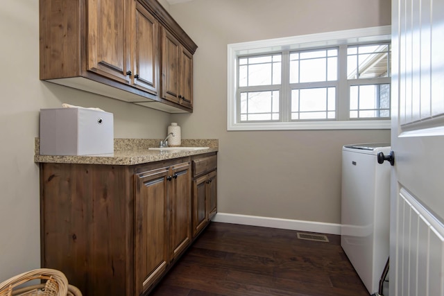 clothes washing area with cabinets, sink, a healthy amount of sunlight, and dark hardwood / wood-style floors