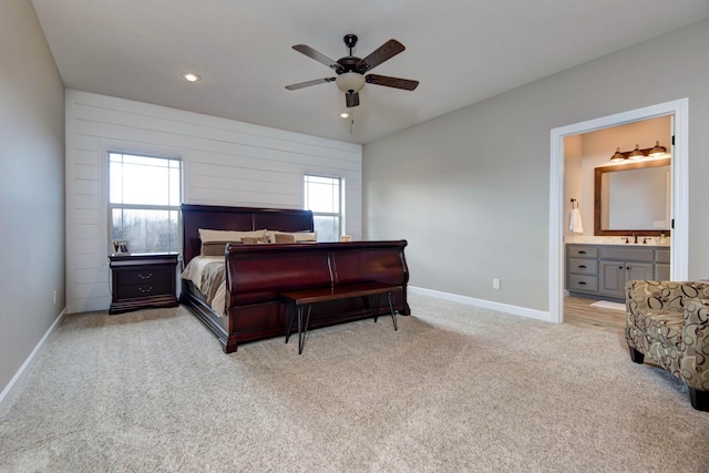 carpeted bedroom featuring multiple windows, ensuite bath, ceiling fan, and wooden walls