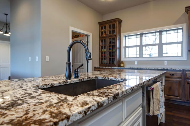 kitchen featuring light stone counters, sink, and a chandelier