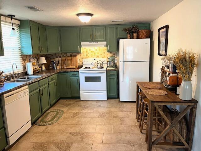 kitchen with decorative backsplash, white appliances, sink, and green cabinetry