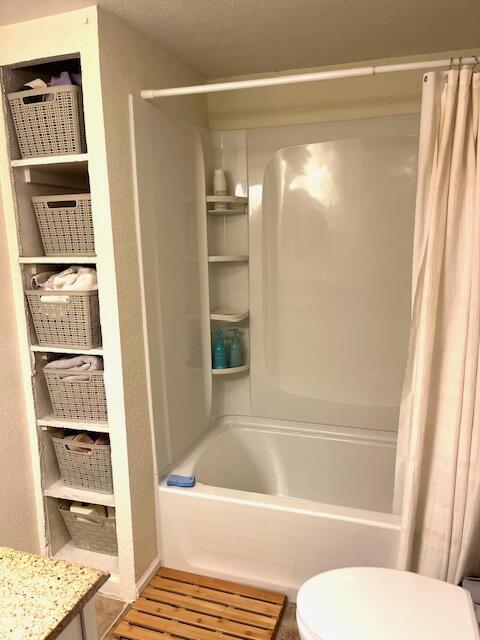 full bathroom with a textured ceiling, vanity, shower / bath combo, and toilet