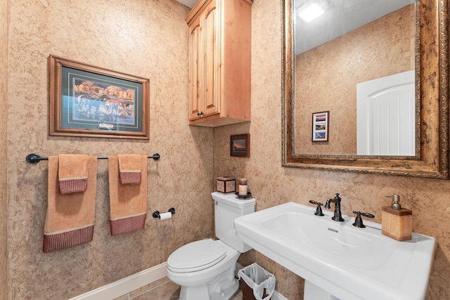 bathroom with toilet, tile patterned flooring, and sink