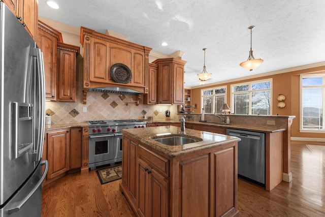 kitchen featuring appliances with stainless steel finishes, dark hardwood / wood-style flooring, sink, hanging light fixtures, and a kitchen island with sink